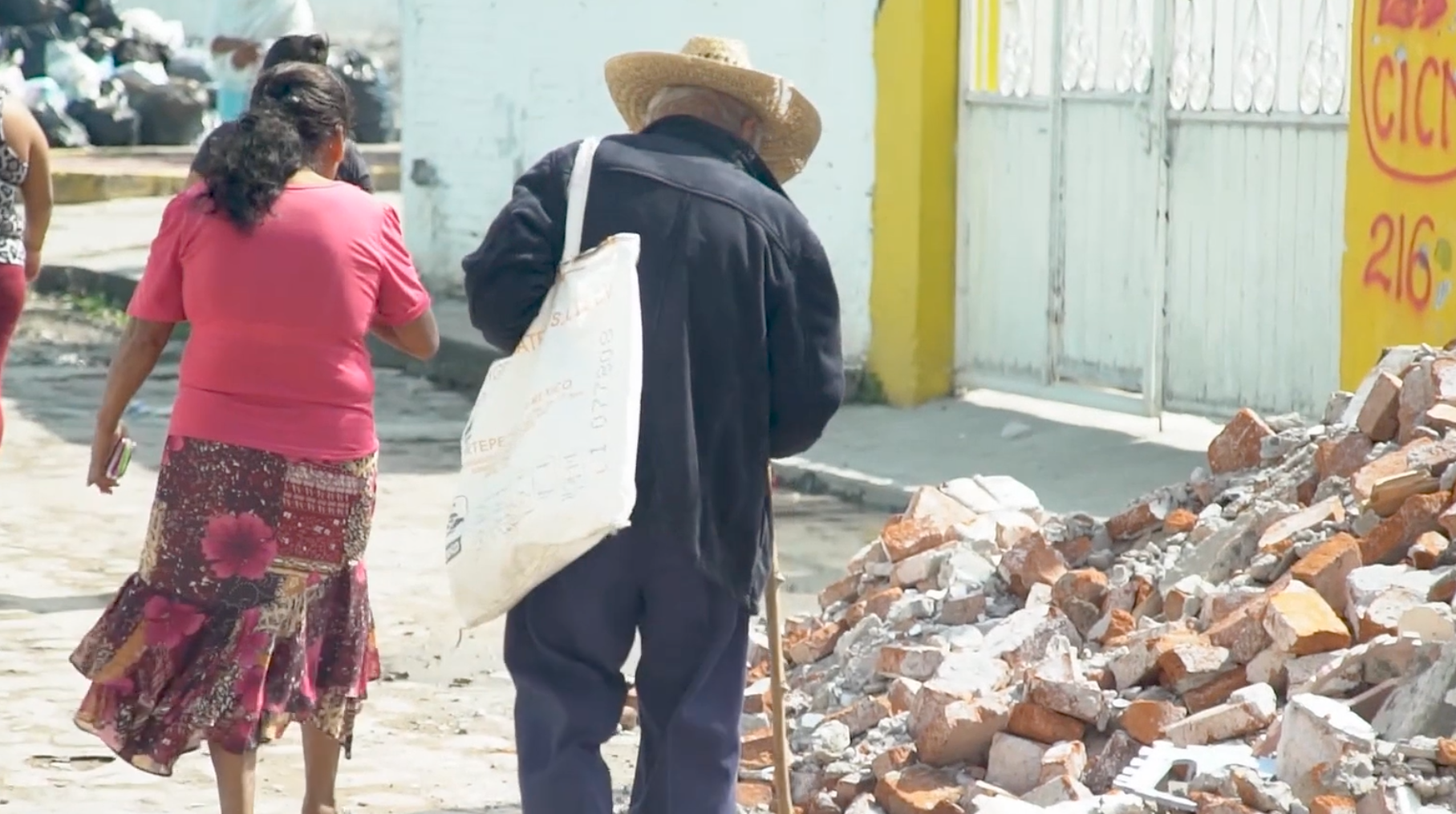 People walk past the destruction from an earthquake