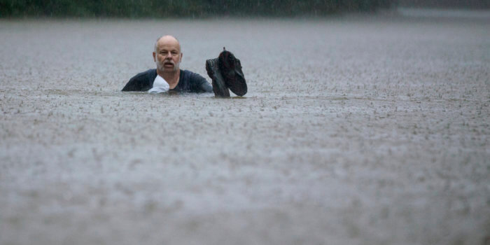 A man wades out through floodwaters caused by heavy rain spawned by Tropical Depression Imelda inundated the area on Thursday, September 19, 2019, in Patton Village, Texas. (Brett Coomer/Houston Chronicle via AP)