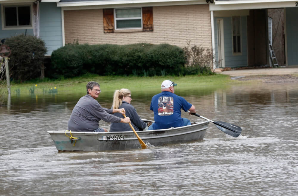 People paddle a boat through floaded neighborhoods