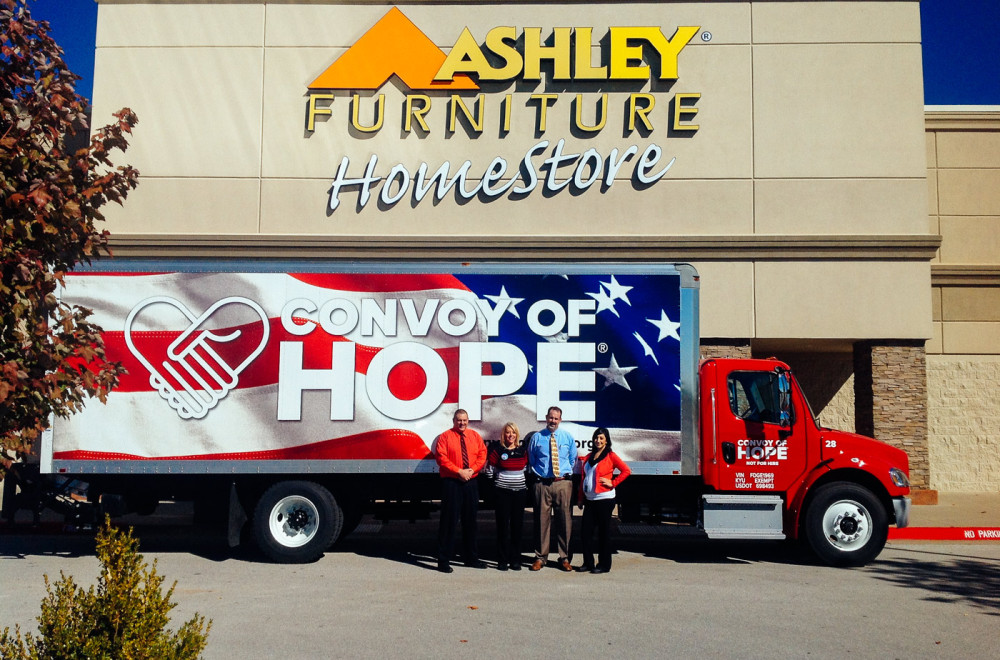 Employees at a regional Ashley Furniture HomeStore stand in front of a Convoy of Hope truck.