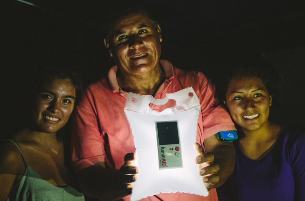 Three people glow in the light of a LuminAID