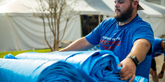 A volunteer carries tarps to help areas devastated by hurricanes