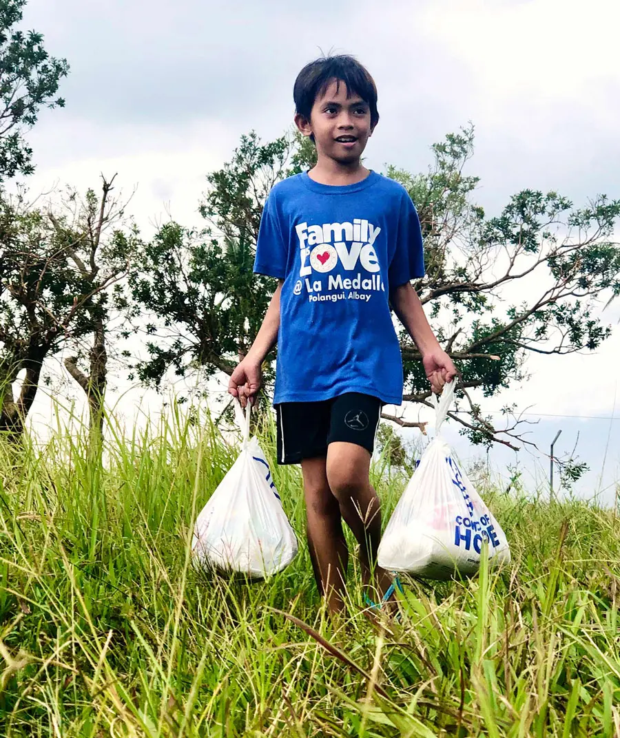 Boy carries Convoy of Hope pages filled with supplies