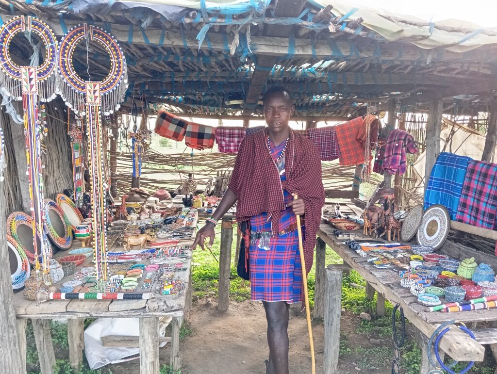 Tome's eldest son stands in a covered booth, surrounded by wares made by Tome.