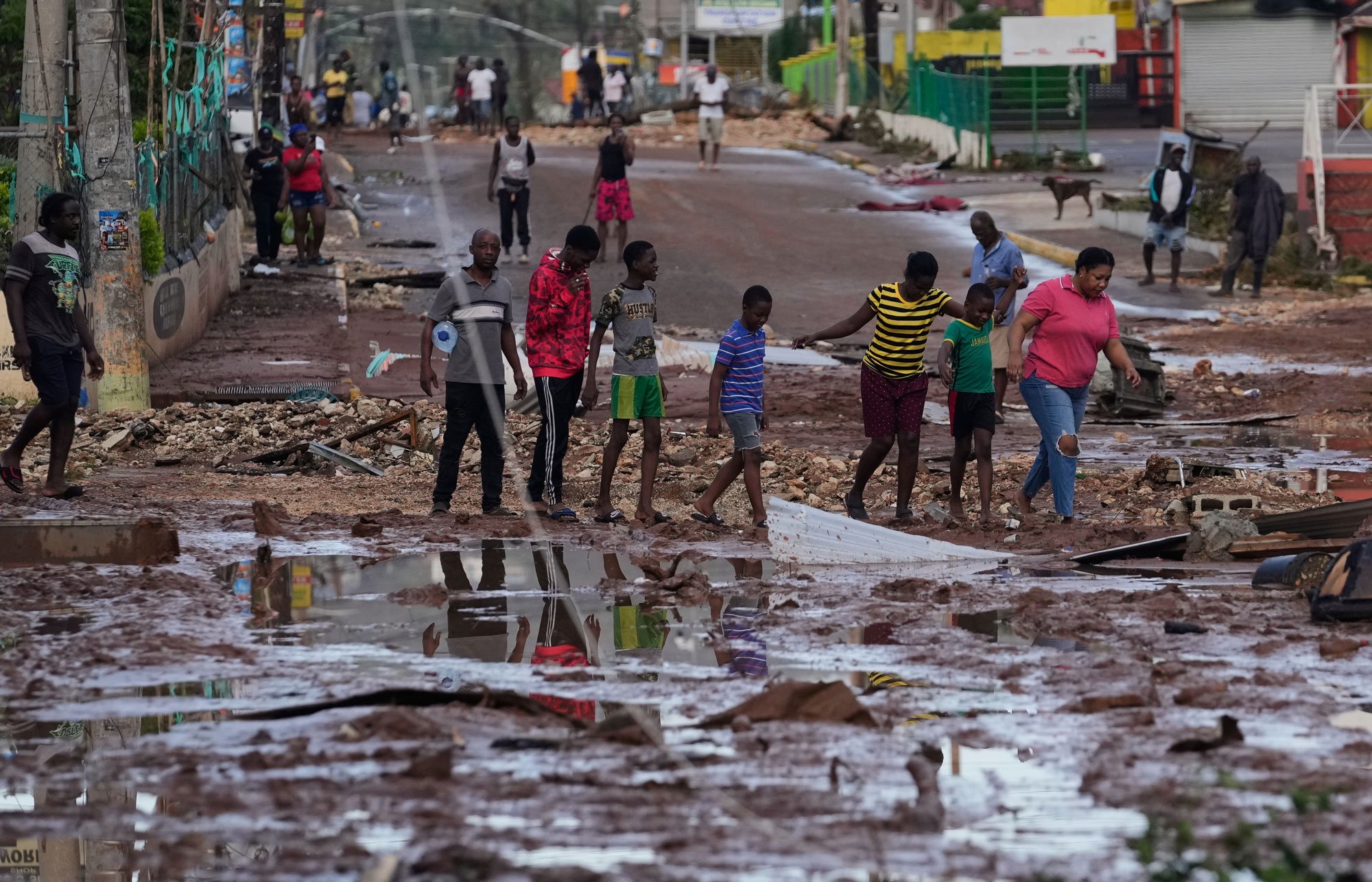 People walk through Santa Cruz, Jamaica, Wednesday, Oct. 29, 2025, after Hurricane Melissa passed. (AP Photo/Matias Delacroix)