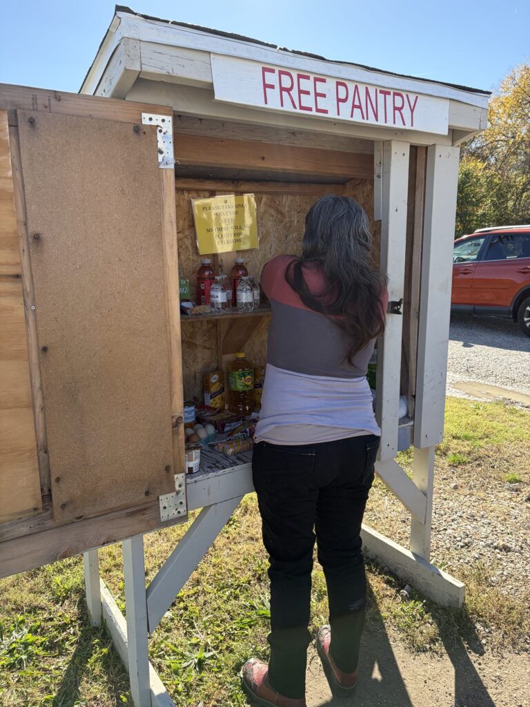 A woman restocks nonperishable food items in a free food pantry.