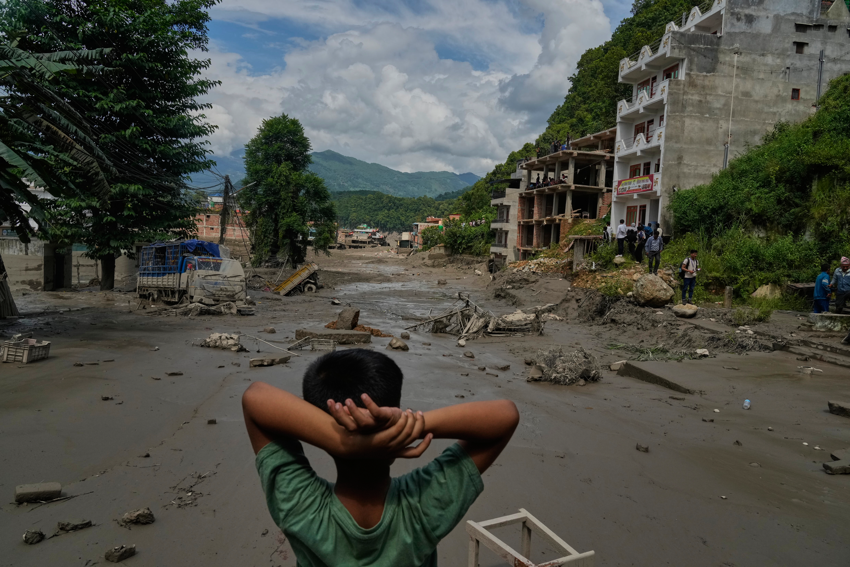 A boy looks at the devastation caused by flash flooding along the Trishuli River in Nepal's Nuwakot district, Wednesday, Aug. 26, 2026. (AP Photo/Niranjan Shrestha)