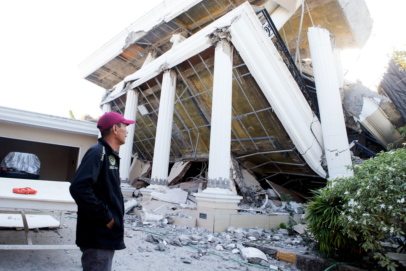 A man examines a building that collapsed during an earthquake in Reo, East Nusa Tenggara province, Indonesia, Monday, Aug. 17, 2026. (AP Photo/Firdia Lisnawati)