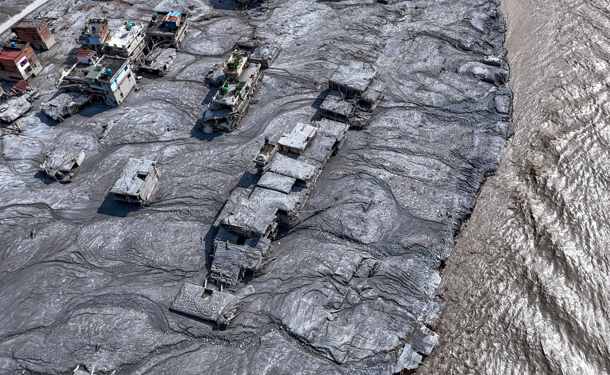 Nuwakot: An aerial view shows damaged structures covered in thick mud and debris along side a swollen river following the devastating flash floods at Devighat village, in Nuwakot district, Nepal, Friday, Aug. 28, 2026. Authorities said the flash floods, triggered by a landslide of ice, mud and rock into a Himalayan river near the Nepal-China border, have left hundreds dead or missing and caused widespread damage across affected districts. (Arun Sharma/PTI via AP)