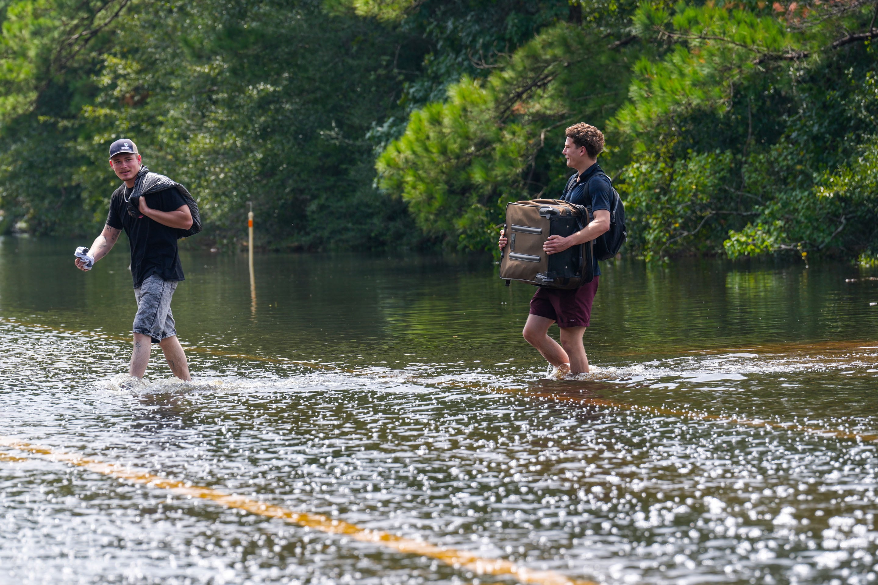 Leroy Cruz, left, and Chad Lawson walk through floodwaters as they make their way to a car to go to work in the aftermath of Tropical Storm Edouard in Kountze, Texas, Wednesday, Sept. 2, 2026. (Brett Coomer/Houston Chronicle via AP)