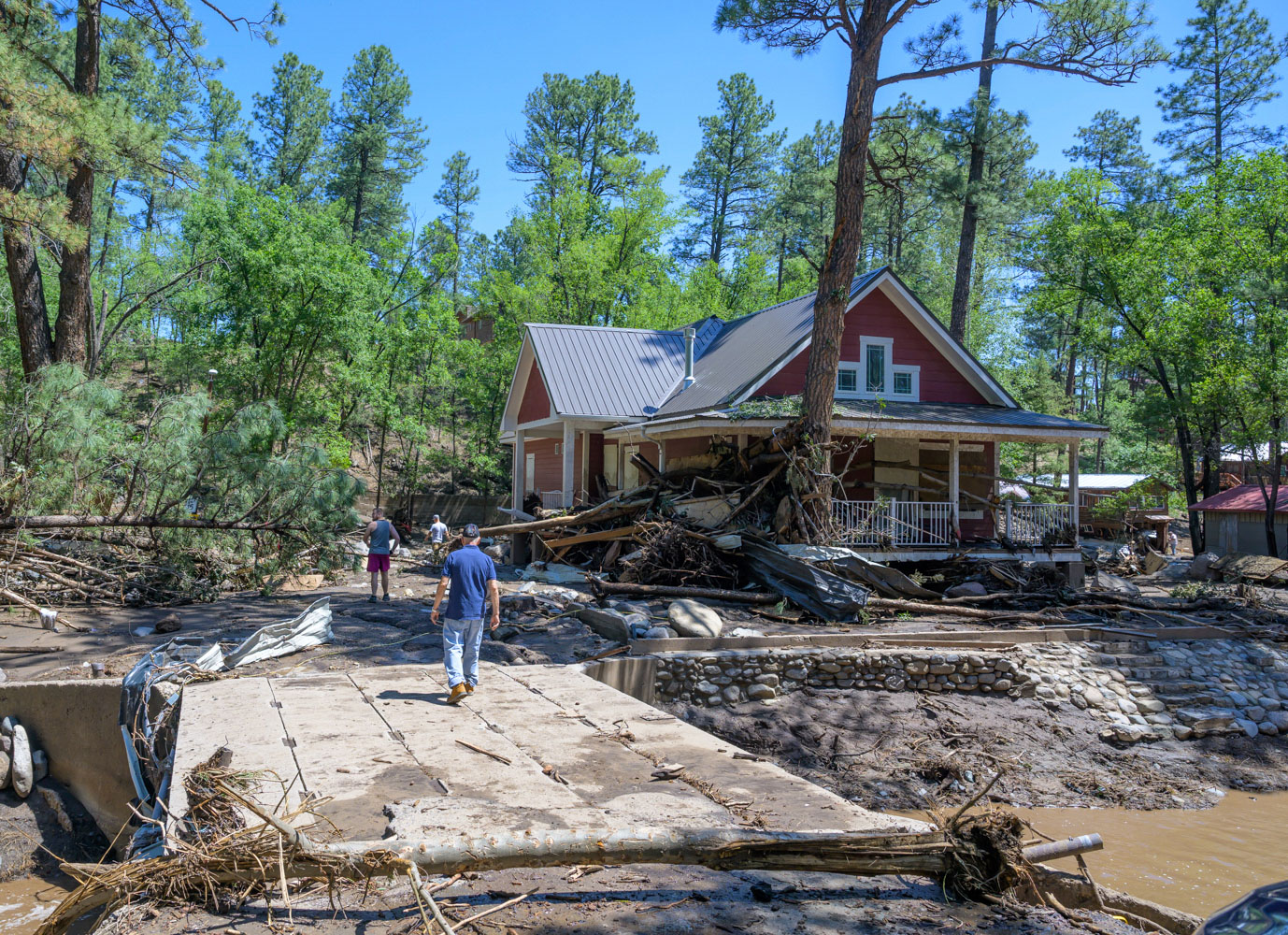 Residents of the town of Ruidoso, N.M., walk back to their neighborhood to find what's left of their homes a day after major flooding washed away properties leaving streets clogged with mud and debris, along the Rio Ruidoso, Wednesday, July 9, 2025, in Ruidoso, N.M. (AP Photo/Roberto E. Rosales)